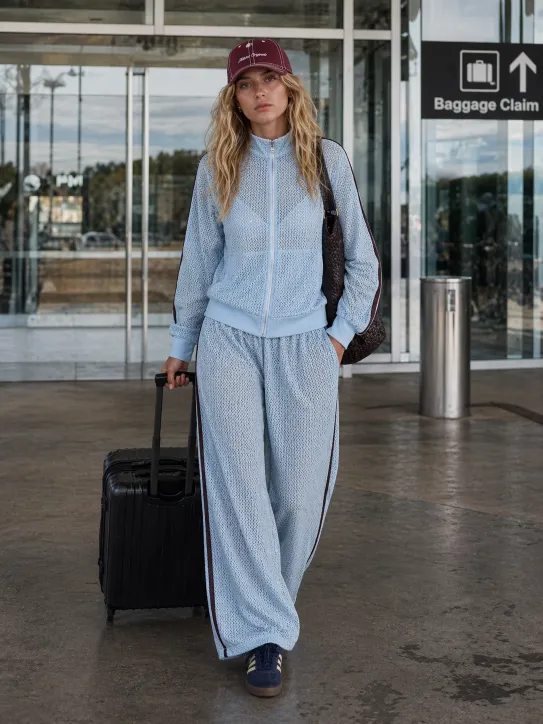 Effortless Airport Style featuring a baby blue crochet track set, navy sneakers, and burgundy cap