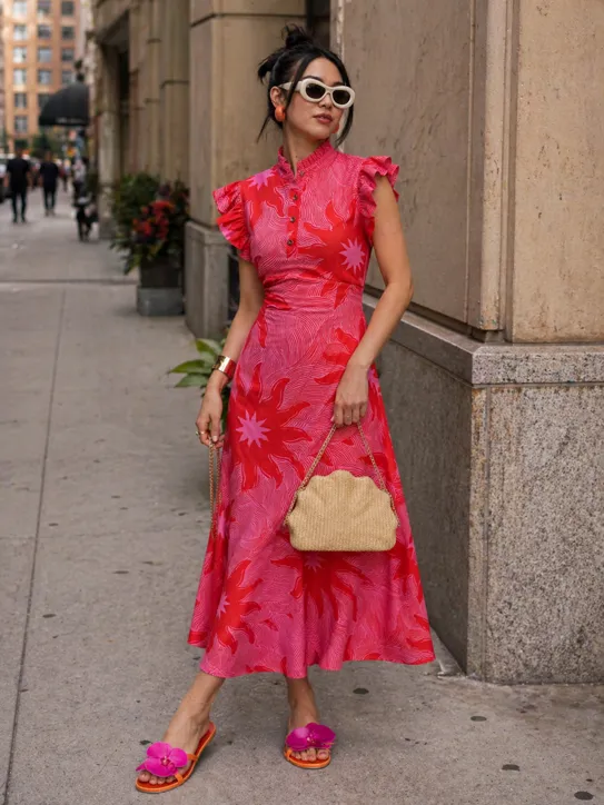 Vibrant Statement outfit featuring a red soleil print dress, straw clutch, and orange floral sandals.